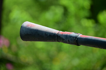 Partial view to the canon barell of a T-54 Tank in front of blurred, green background. 
