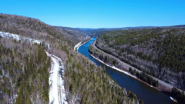 Panoramic aerial view of a legendary salmon river. The winding Matapedia River flows through the snow-capped mountains of the Matapedia Valley. Routhierville, Quebec, Canada, Winter 2025.