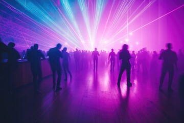 Blurred silhouettes of people dancing in a nightclub illuminated by vibrant laser lights.
