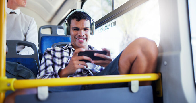 Happy man, bus and playing games with phone for travel, local commute or entertainment in city. Male person, traveler or mobile gamer with smile or headphones for online streaming in public transport