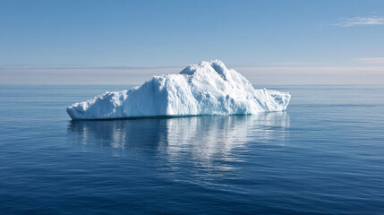 Iceberg A23a majestically floats in the dark blue waters of the Southern Ocean, its reflection shimmering on the surface against a clear sky