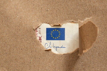 A hole in the paper through which the EU flag is visible on a ten euro note, money