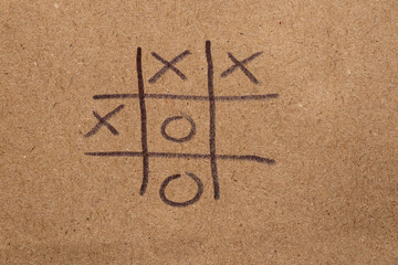 Children's game tic-tac-toe drawn on brown paper with black marker, tic-tac-toe