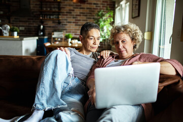Senior lesbian couple relaxing on the couch together with laptop
