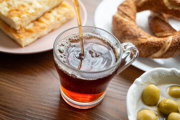 Local Turkish breakfast table Turkish tea, su boregi, green olives and simit bagel
