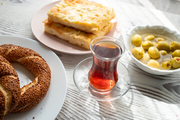 Local Turkish breakfast table Turkish tea, su boregi, green olives and simit bagel