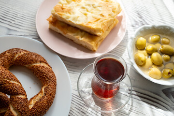 Local Turkish breakfast table Turkish tea, su boregi, green olives and simit bagel