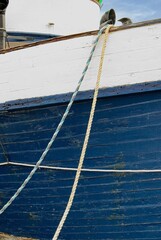 Mooring lines lead up over bulwark of wooden hull ship