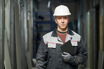 Portrait of confident Caucasian builder with tablet in hand standing still in empty room