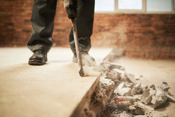 Medium close up of unrecognizable worker using jackhammer to demolish old cement on floor