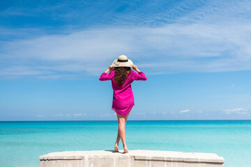 Young beautiful girl in hat on the beach, woman in bright pink dress