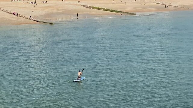 man stand up paddle board at beach on ocean, travel vacation adventure, hastings east sussex uk