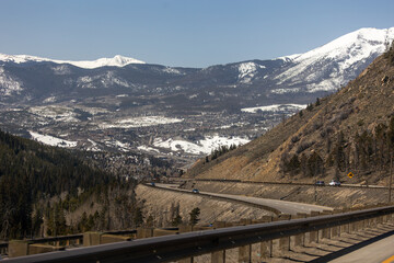 Fototapeta premium Scenic drive on I-70 in Colorado with stunning views of the snow-covered Rocky Mountains under clear blue skies, perfect for a winter road trip