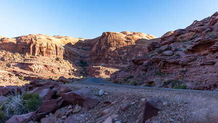 Early morning drive through the rugged dirt roads of Moab, Utah, with golden sunlight casting dramatic shadows across red rock canyons and remote desert landscapes