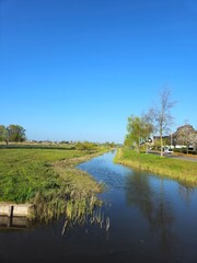 Canal with a gorgeous bright green weeping willow over hanging the canal banks. Vibrant woodland landscape in Spring in a public park.