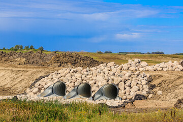 Field with three large pipes and a pile of rocks