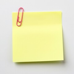 Yellow sticky note with pink paperclip attached to the top left isolated on gray background