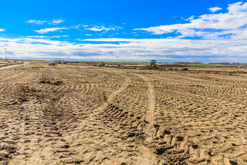 Field with a tractor and a few cars in the background
