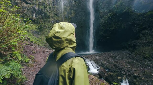 Excited woman with backpack admire waterfall on Madeira island, trekking on levada Madeira