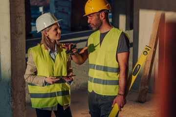 Construction workers discussing project using walkie talkie and tablet