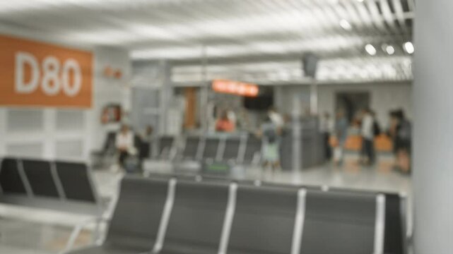 Blurry photo of people waiting at d80 gate in an airport with a defocused bokeh effect, highlighting the traveling experience in a modern terminal setting.