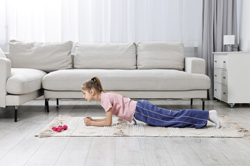 Little girl doing plank exercise at home. Morning routine