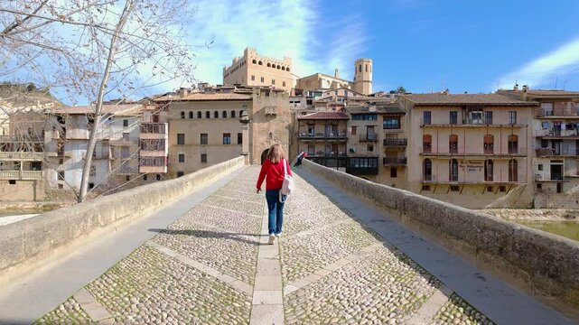 Tourist woman crossing the medieval stone bridge that leads to the town of Valderrobres, Teruel.