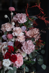 Delicate pink preserved flowers in a vase, in a dark interior. Tall black candles and warm light. An atmosphere of coziness and luxury. Women's day, mother's day, valentine's day.