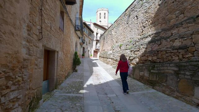 Tourist woman walking through the narrow streets of the medieval village of Valderrobres, Matarrana.