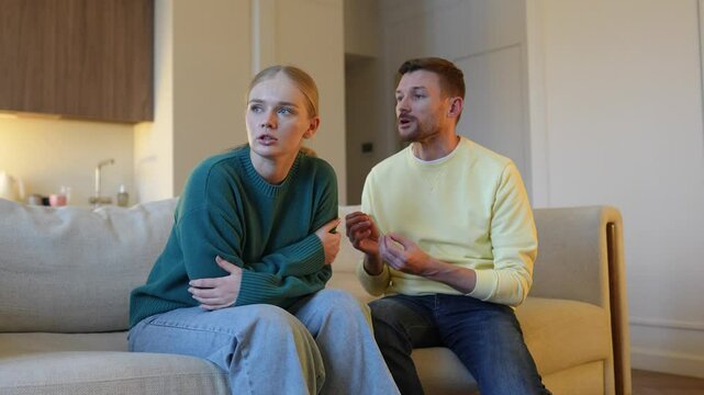 Wife discovers infidelity. Ashamed lying man tries to explain to furious hurt irritated woman, couple conflict on couch, serious argument unfolds, break up, cheating affair and lost trust in family