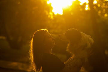 Young Caucasian woman hugging her border collie dog while walking in the park. 