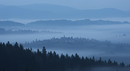 Natural, beautiful nature images a misty landscape with a forest in the foreground and a village in the background under a blue sky