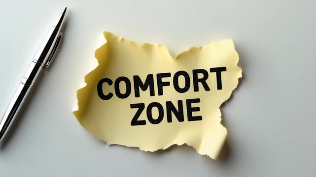 Message about comfort zone on a ripped paper with a pen against a white backdrop.