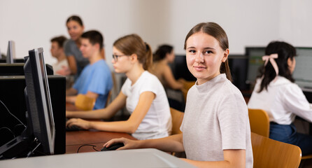 Portrait of interested teen girl during lesson in computer room of school computer class
