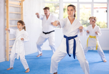 Parents with children athletes starting position and studying repeating sequence of punches and painful techniques in karate kata technique. Oriental martial arts, training and obtaining black belt © JackF