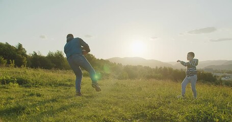Family, sports, fatherhood, childhood memories, outdoor activities. Father and Son Playing Rugby in Park at Sunset, Heartwarming video of a father and son playing rugby together outdoors in park
 - Powered by Adobe