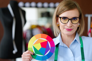 fashion designer holding color wheel indicates design process and creativity. woman wearing glasses...