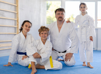 Cheerful friendly sporty family with tween children dressed in traditional white kimonos posing...