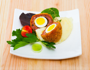 Scotch egg with quail eggs served with mashed potatoes and herbs - traditional English dish