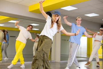 Obraz premium Cool talented teens in casual wear exercising modern dance moves in training room