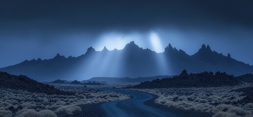 Naklejka premium Moonlit desert road winding towards majestic mountains, crepuscular rays illuminating the scene. Travel photography