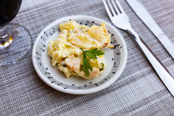 Salad with boiled potatoes, smoked sausages, pickles, eggs garnished with mayonnaise and mustard sauce