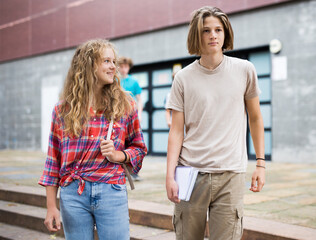 Teenager boy and girl going home after classes in school.