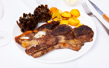 Popular Spanish dish of grilled beef steak Churrasco, potatoes and artichokes