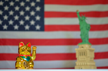 Golden maneki neko and statue of liberty with usa flag