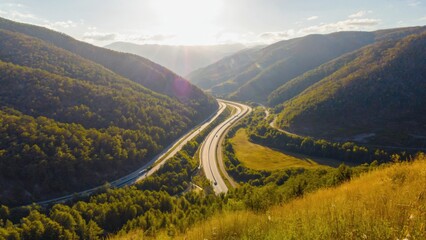 Highway between mountain peaks, with clear sunny skies.