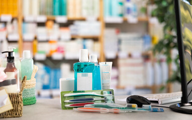 Refreshing mouthwash and a set of toothbrushes on the counter near the computer. Dental care kit against the background of a medicine rack in a pharmacy