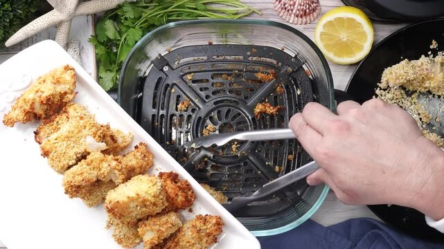 Using an air fryer to make homemade fish sticks for a quick and easy dinner,  Breaded fish sticks being cooked in an air fryer.  Easy seafood dinner meal.