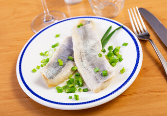 Pieces of raw pickled herring served with onions on platter plate