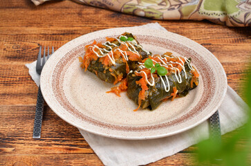a portion of delicious cabbage rolls on a plate with vegetables and herbs close-up